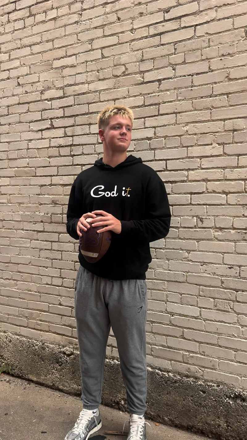Young man in the black God it. hoodie holding a football
